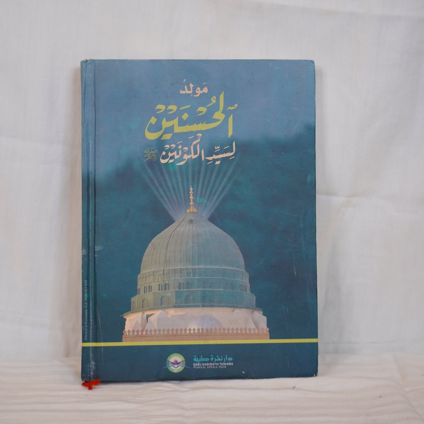 "Moulid ul Husnain li Sayyedil Kounain by Abdul Basheer Saqafi Pilakkal – A book with Arabic calligraphy and an image of the Prophet’s Mosque."