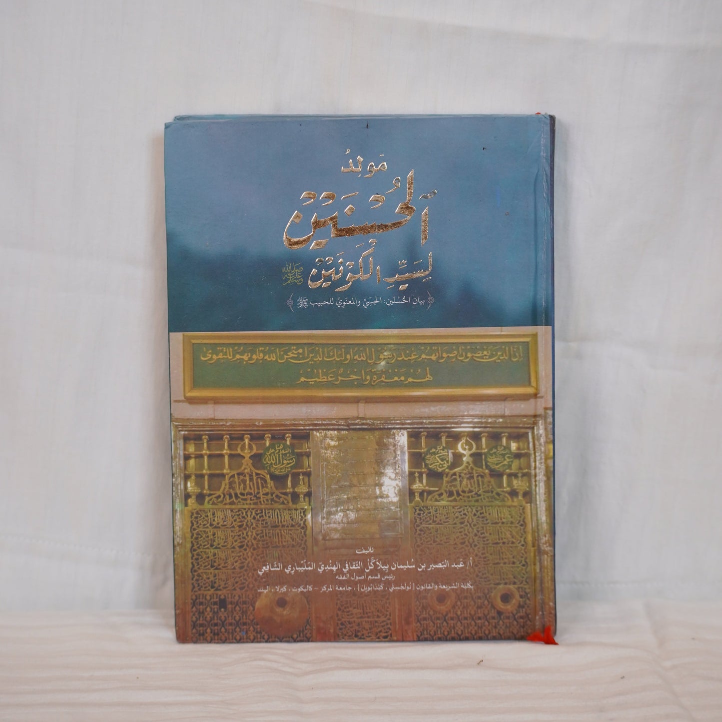 Moulid ul Husnain li Sayyedil Kounain by Abdul Basheer Saqafi Pilakkal – A book with Arabic calligraphy and an image of the Prophet’s Mosque.