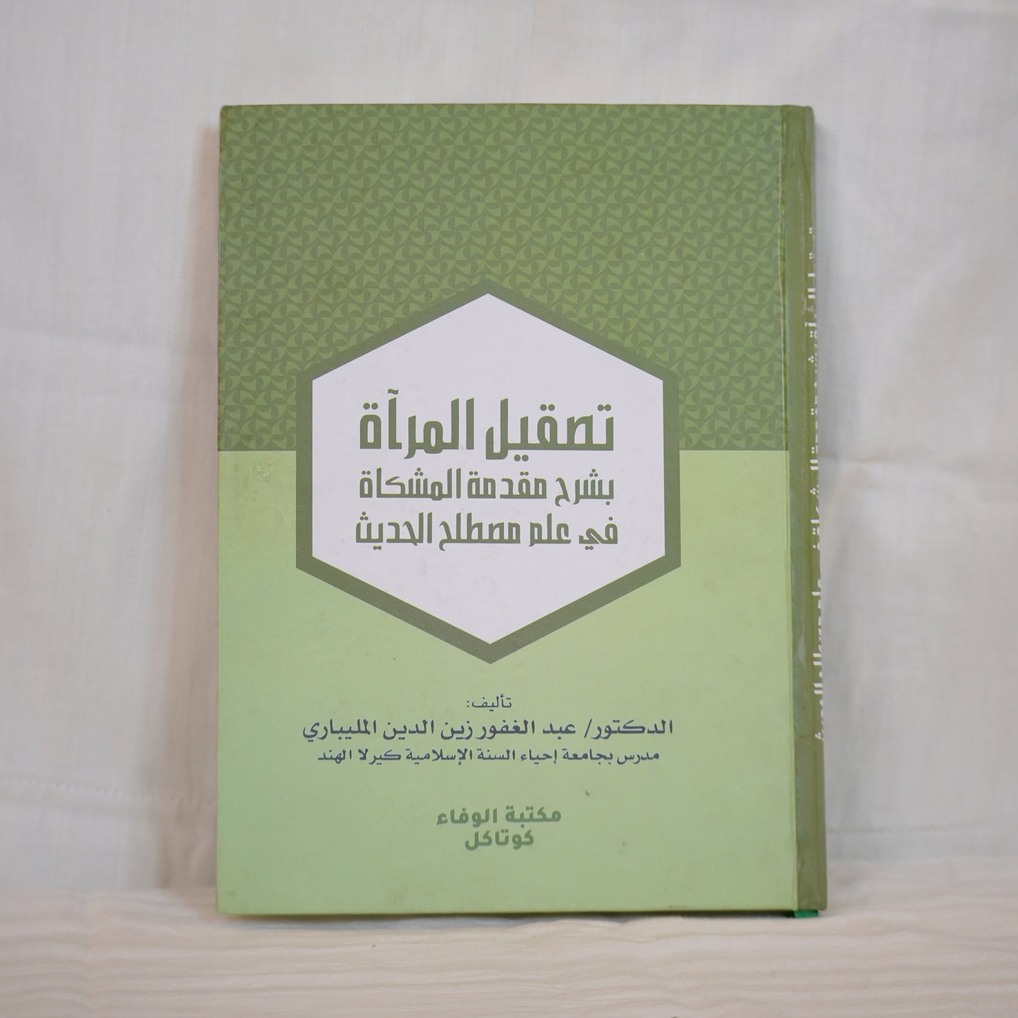 A book cover in Arabic with a green design and a hexagonal white label in the center. The book is titled 'تصقيل المرآة بشرح مقدمة المشكاة في علم مصطلح الحديث' and authored by Dr. Abdul Ghafoor Zainuddin Al-Malibari. Published by Wafa Books, Kottakkal."