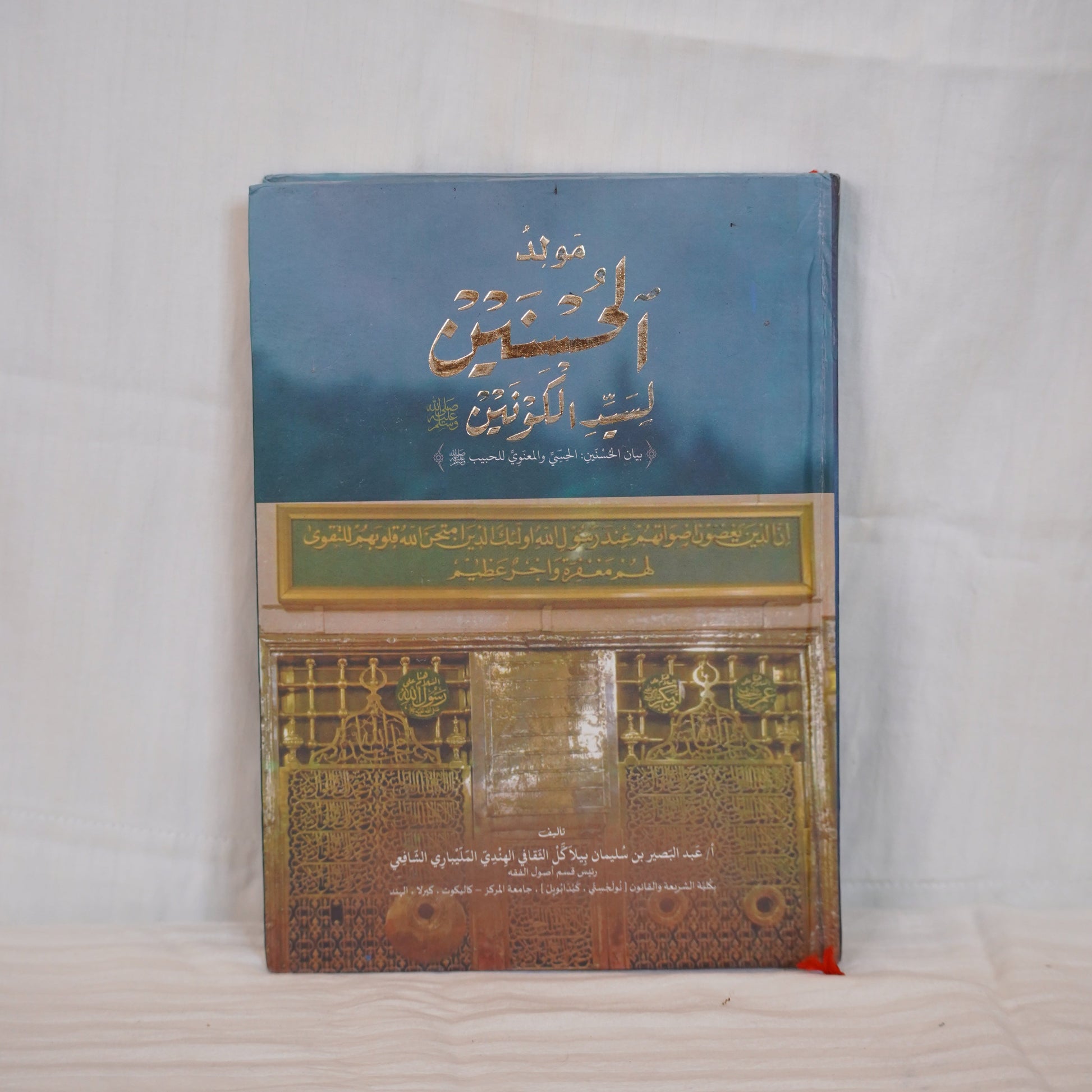 Moulid ul Husnain li Sayyedil Kounain by Abdul Basheer Saqafi Pilakkal – A book with Arabic calligraphy and an image of the Prophet’s Mosque.