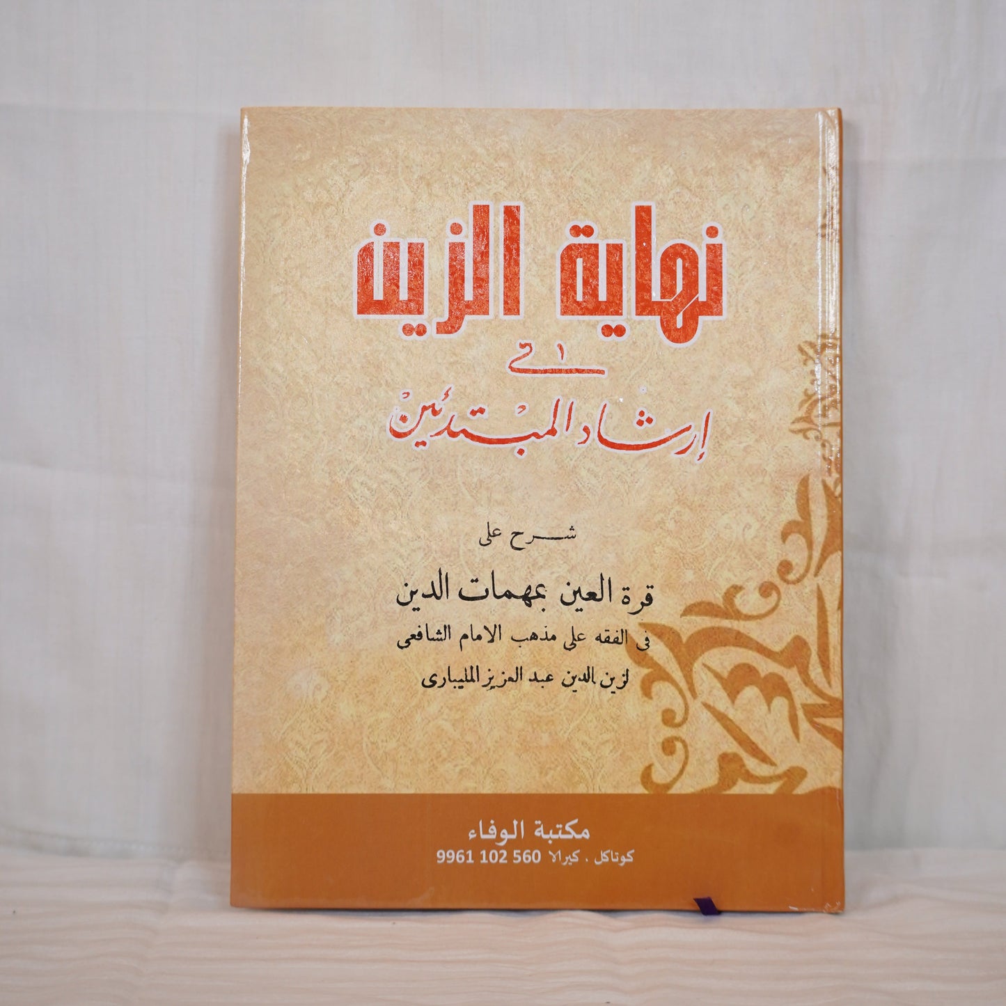 Nihayat Al-Zain Fi Irshad Al-Mubtadi’een – Arabic hardcover book on Shafi'i Fiqh, displayed upright against a white cloth background.